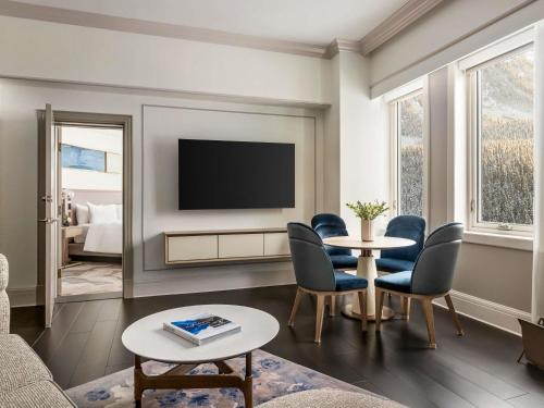a living room with a tv and a table and chairs at Fairmont Château Lake Louise in Lake Louise