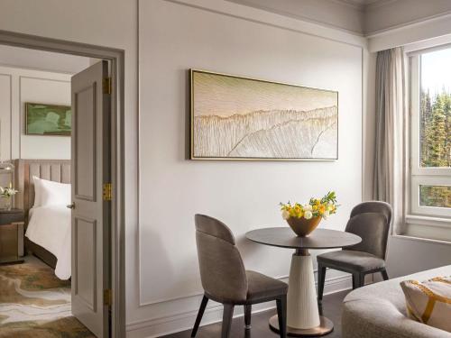a room with a table and chairs and a bed at Fairmont Château Lake Louise in Lake Louise