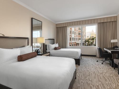 a hotel room with two beds and a desk at Hamilton Princess & Beach Club A Fairmont Managed Hotel in Hamilton