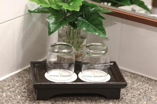two glass jars on a black tray with a plant at Royal Phuket City Hotel in Phuket Town