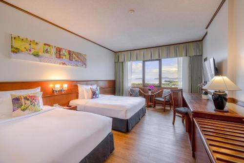 a hotel room with two beds and a desk at Royal Phuket City Hotel in Phuket Town
