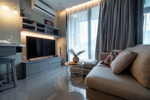 a living room with a couch and a television at Suite Celeste 1BR Sunset RooftopCitygate Kamala in Kamala Beach