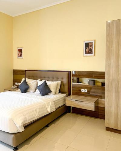 a bedroom with a large bed with a wooden headboard at Alloro Boutique Hotel Pacitan in Pacitan