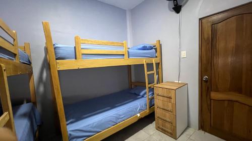 a room with two bunk beds and a wooden door at Habitaciones en Shekinah House, Data de Villamil in Data de Villamil