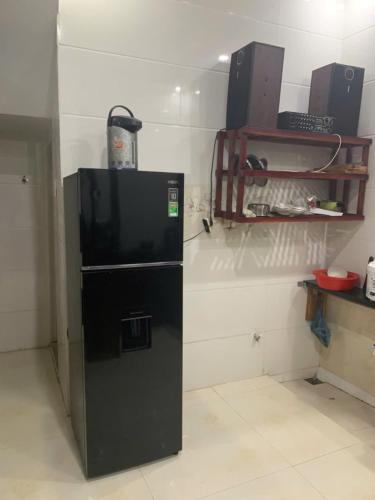 a black refrigerator in a room with a shelf at Danh Tài Homestay in Kon Rung (1)