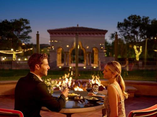 a man and a woman sitting at a table in front of a dinner table at Fairmont Grand Del Mar in San Diego
