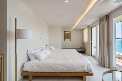 a white bedroom with a bed and a window at 해운대 웨이브 Haeundae wave in Busan