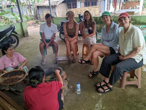 a group of people sitting on chairs in the dirt at Coffee Homestay Tetebatu in Tetebatu
