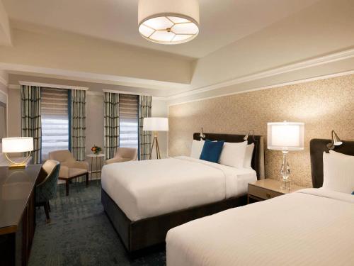 a hotel room with two beds and a desk at Fairmont Empress Hotel in Victoria