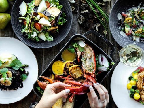 a person holding a lobster on a table with plates of food at Fairmont Vancouver Airport In-Terminal Hotel in Richmond