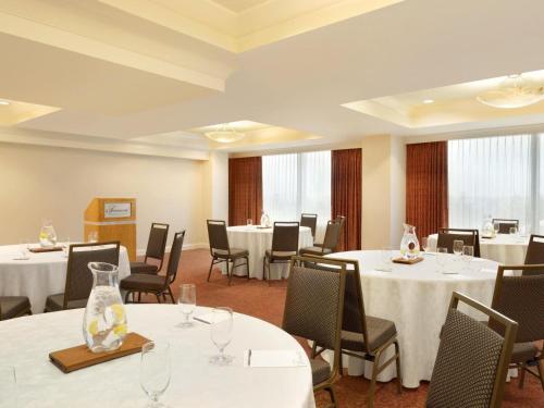 a dining room with tables and chairs with white tablecloths at Fairmont Vancouver Airport In-Terminal Hotel in Richmond