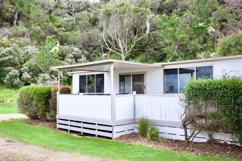 a white house with a fence and bushes at BIG4 Wilsons Prom Holiday Park in Yanakie