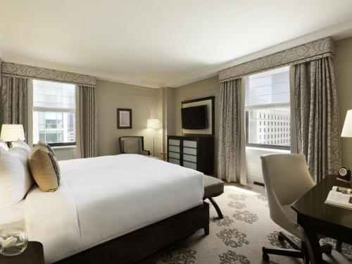 a hotel room with a bed and a desk and window at Fairmont Hotel Vancouver in Vancouver
