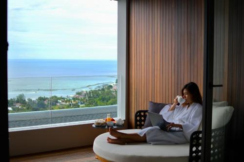 a woman sitting in a chair talking on a cell phone at Anzhu Seamate Villa Samui in Amphoe Koh Samui