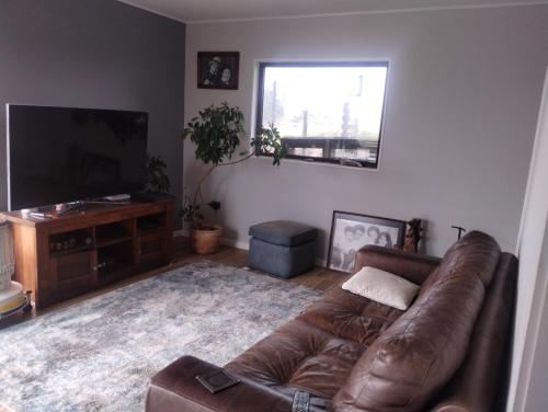 sala de estar con sofá de cuero y TV de pantalla plana en Lomas de Puerto Varas, en Puerto Varas
