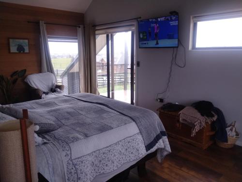 Un dormitorio con una cama y un televisor en la pared. en Lomas de Puerto Varas, en Puerto Varas