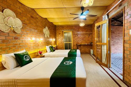 two beds in a room with a ceiling fan at Mekong Rustic Riverside in Ấp An Nhơn (3)