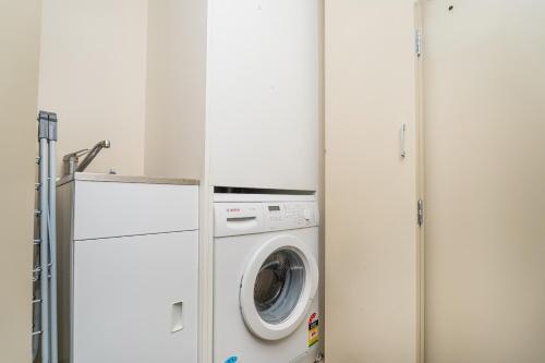a washer and dryer in a white laundry room at Esplanade Apartments in Whitianga