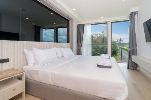 une chambre avec un grand lit blanc avec une grande fenêtre dans l'établissement Ozone 2 Bed Condominium in Splendid Laguna Area, à Laguna Phuket