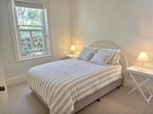 a bedroom with a bed with a striped blanket and a window at Charming Sandstone Villa in the heart of Norwood in Rose Park