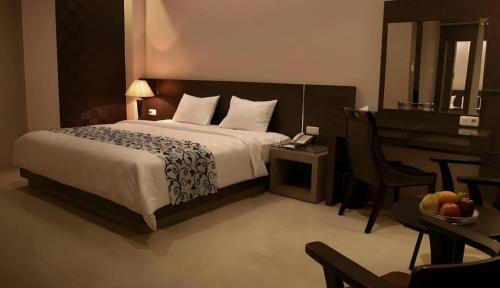 a bedroom with a bed and a table with a telephone at Mega Permata Hotel in Padangsidimpuan