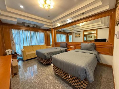 a bedroom with two beds and a couch and a mirror at New Siya in Maha Sarakham