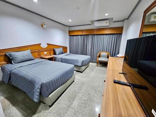 a hotel room with two beds and a flat screen tv at New Siya in Maha Sarakham