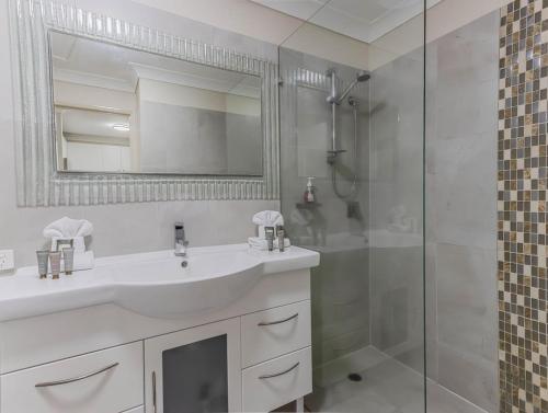 a white bathroom with a sink and a shower at Tweed Coast Haven in Tweed Heads