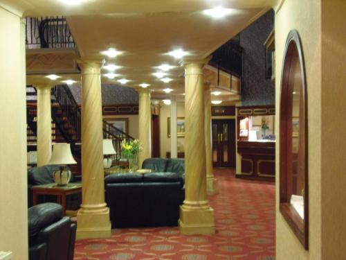 a living room with couches and tables and columns at Lakeside International Hotel in Camberley