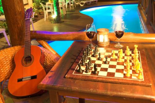 a guitar and two glasses of wine and a chessboard at Pousada Laguna Blue in Paraty