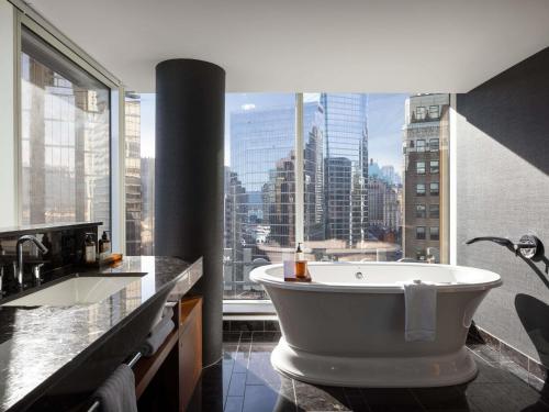 a bath tub in a bathroom with a large window at Fairmont Pacific Rim in Vancouver