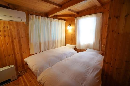 two beds in a room with a window at 日は沈みまた昇る in Nirasaki