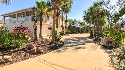 una pasarela frente a una casa con palmeras en Beach Home with Amazing Oasis Pool Spa Waterfall Fire Pit Bikes, en Marineland