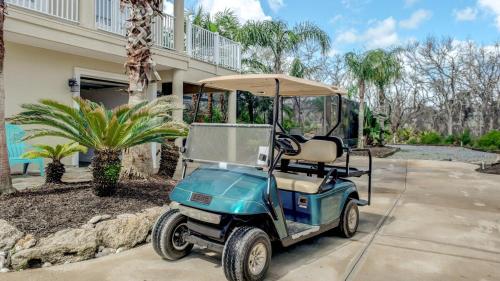 un carrito de golf estacionado frente a una casa en Beach Home with Amazing Oasis Pool Spa Waterfall Fire Pit Bikes, en Marineland