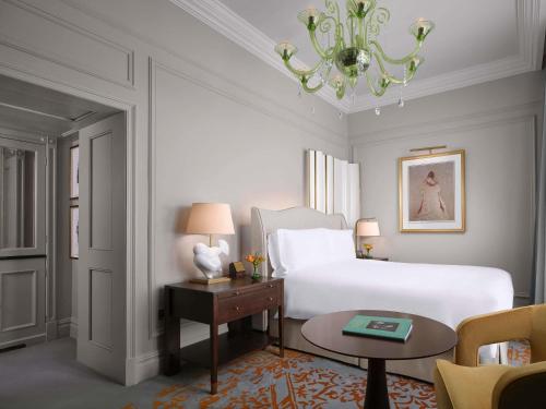 a bedroom with a bed and a table and a chandelier at The Savoy in London