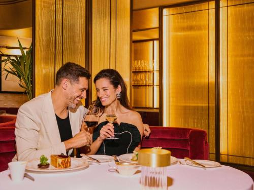 a man and woman sitting at a table with wine glasses at The Savoy in London