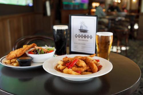 a table with two plates of food and two glasses of beer at Mortdale Hotel in Mortdale