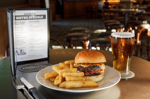 a plate with a hamburger and french fries and a glass of beer at Mortdale Hotel in Mortdale