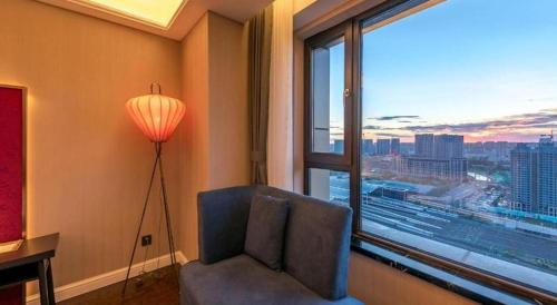 a room with a chair and a large window at James Joyce Coffetel Harbin West High-speed Railway Station Wanda Plaza in Harbin