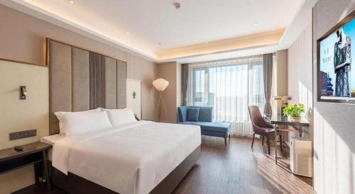 a hotel room with a large white bed and a chair at James Joyce Coffetel Harbin West High-speed Railway Station Wanda Plaza in Harbin