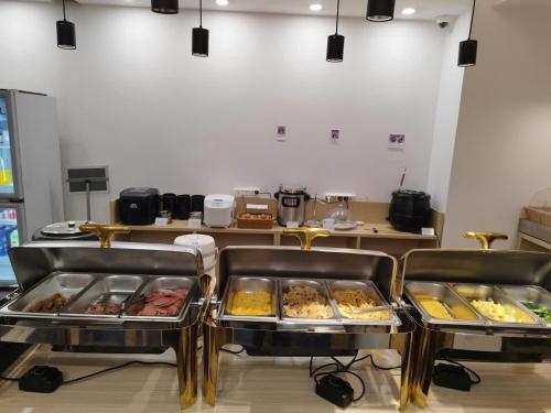 a buffet line with trays of food in a kitchen at Hotel Yah Hanoi & Spa in Hanoi