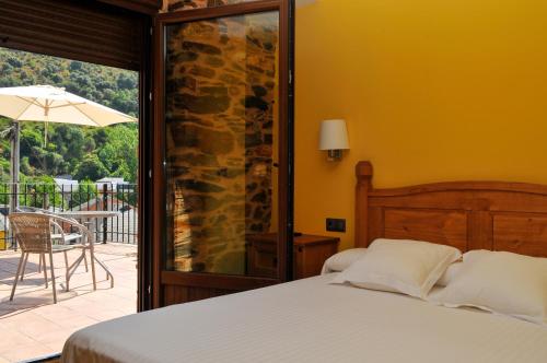 a bedroom with a bed and a patio with an umbrella at Hotel Rural Pescadores in Sobrado