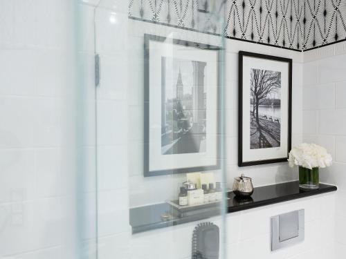 a bathroom with a shower with two pictures on the wall at Fairmont Hotel Vier Jahreszeiten in Hamburg