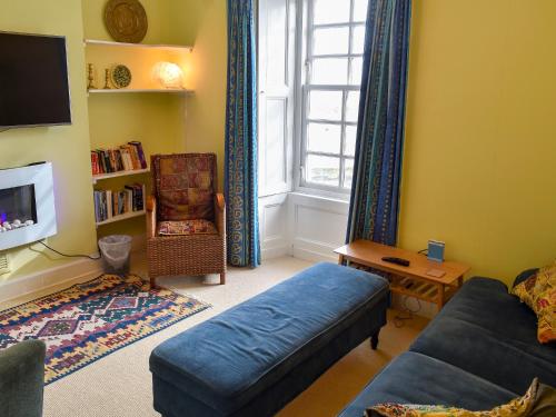 a living room with a blue couch and a window at St Abbs - Lighthouse Retreat in Saint Abbs