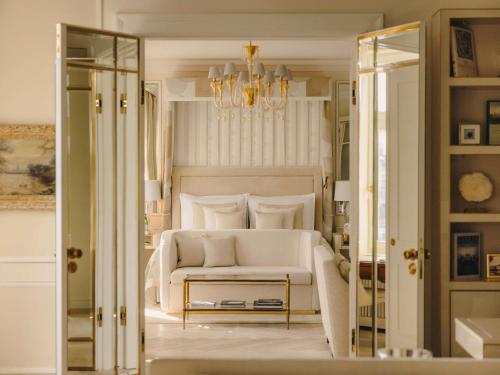 a bedroom with a white bed and a chandelier at Fairmont Hotel Vier Jahreszeiten in Hamburg