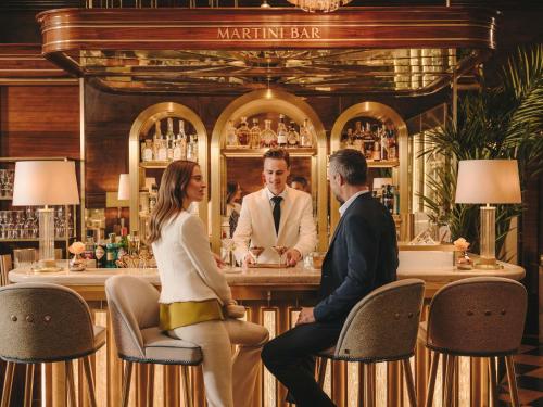 a man and a woman sitting at a bar at Fairmont Hotel Vier Jahreszeiten in Hamburg