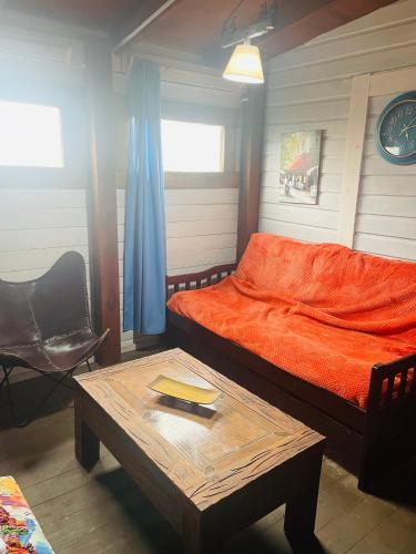 a bedroom with a bed with an orange sheets and a table at Hermosa cabaña en Barra de Valizas in Barra de Valizas