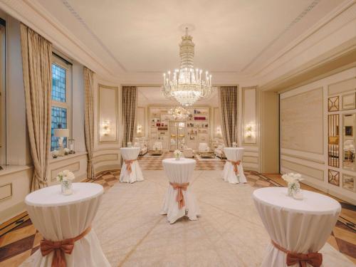 a room with white tables and a chandelier at Fairmont Hotel Vier Jahreszeiten in Hamburg