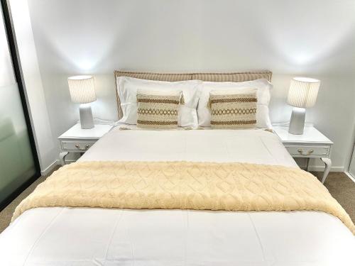 a bedroom with a large white bed with two night stands at Modern apartment in the city center in Auckland