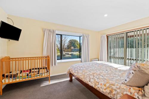 a bedroom with a crib and a large window at 130 Jacks Pass Road in Hanmer Springs